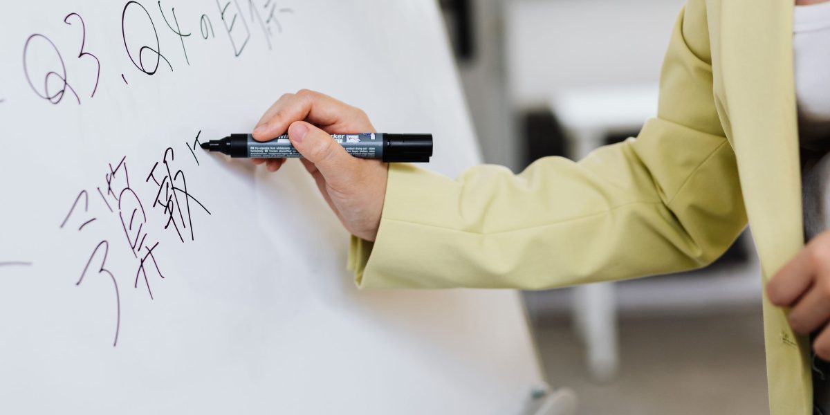 A person looks thoughtfully at a whiteboard, planning future business growth.