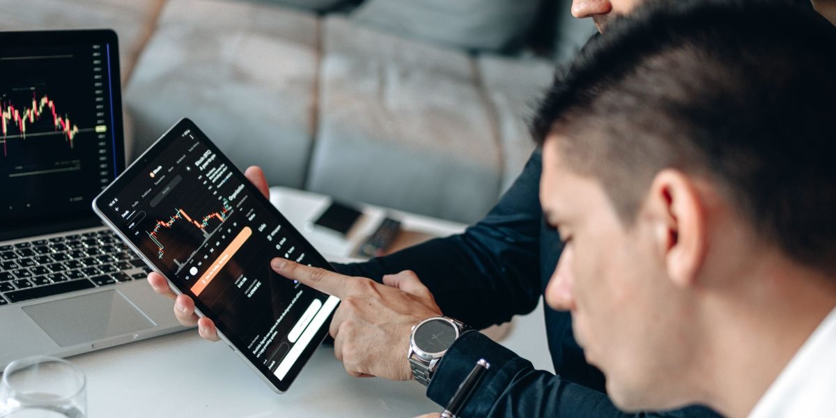 A person thoughtfully analyzes performance data on a tablet, tracking business results.