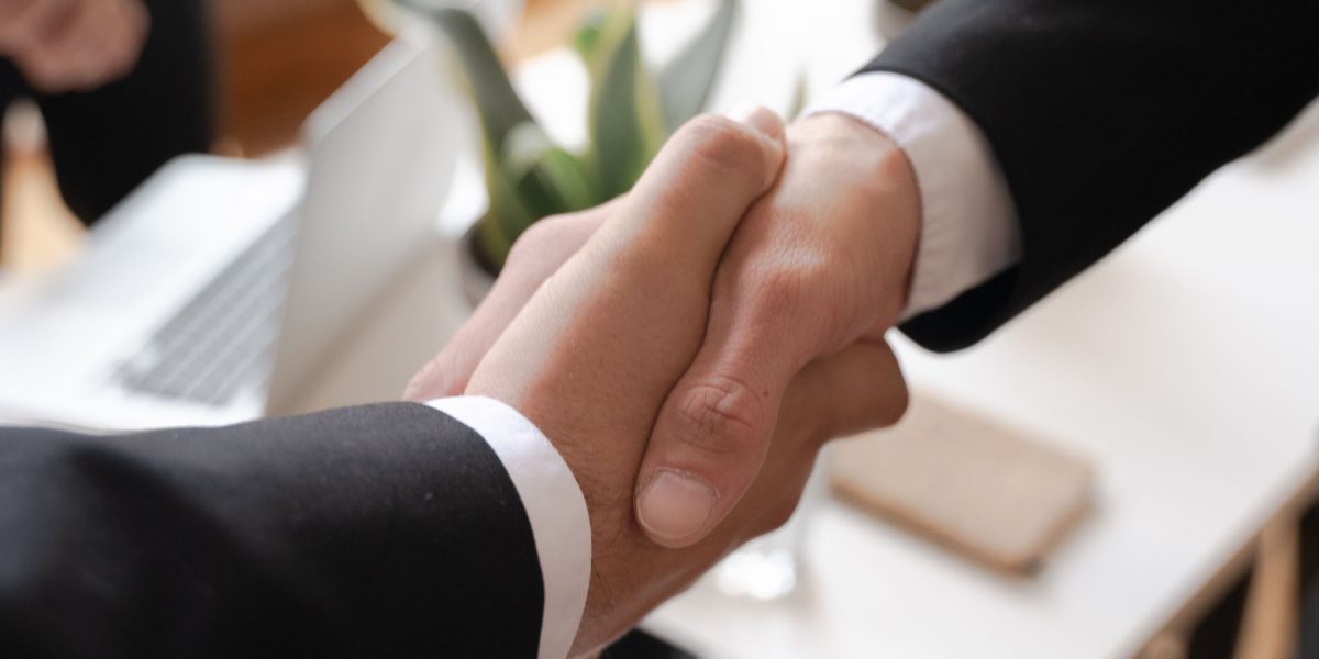 Two professionals shaking hands, symbolizing a successful partnership between merchants and affiliates.