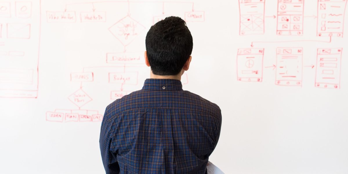 An individual explains ideas on a whiteboard, representing the creation of helpful and engaging content.