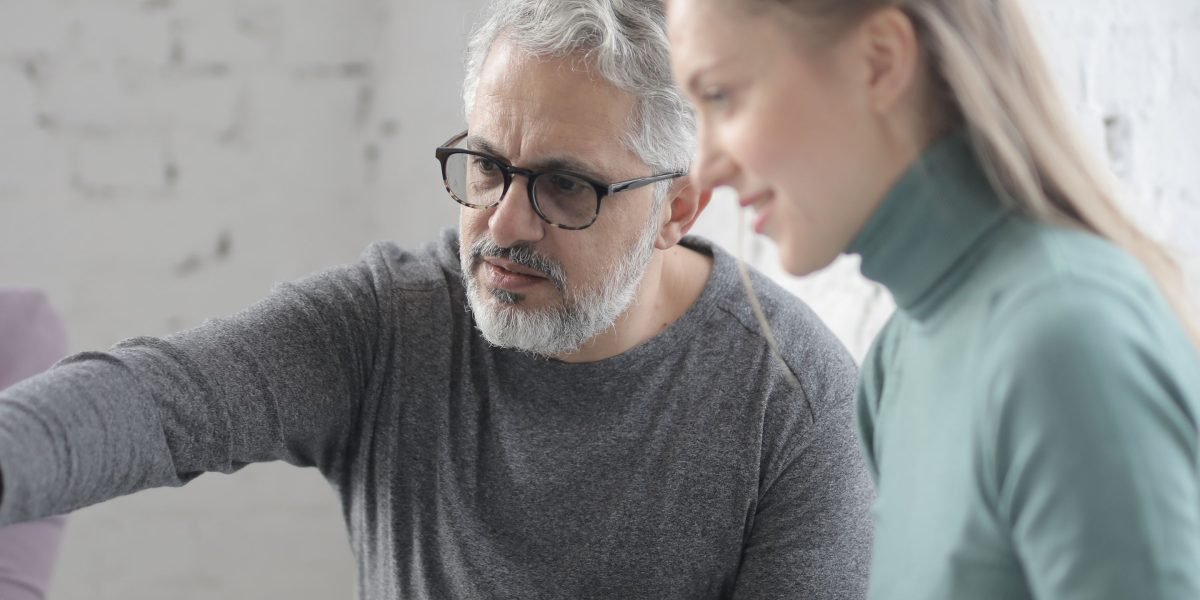 An experienced professional guides a new team member, illustrating the onboarding and support process.