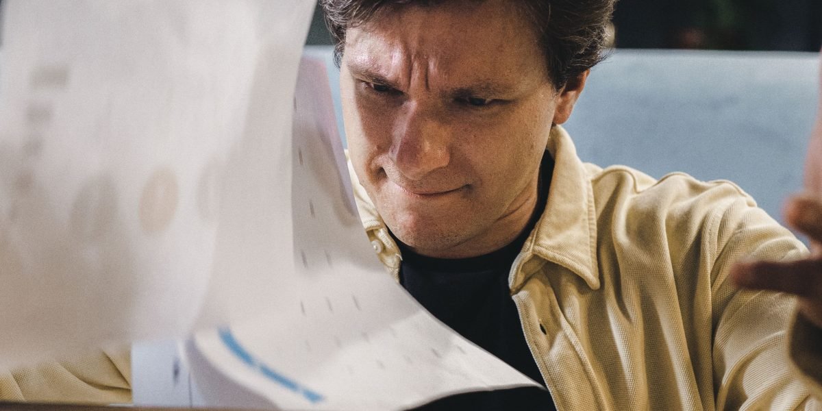 A person looking thoughtful and perhaps overwhelmed by multiple data sources, representing the challenges of fragmented reporting in affiliate marketing.